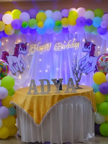 An elegant unicorn-themed setup with pastel balloons and a neon 'Happy Birthday' sign, perfect for a magical celebration.