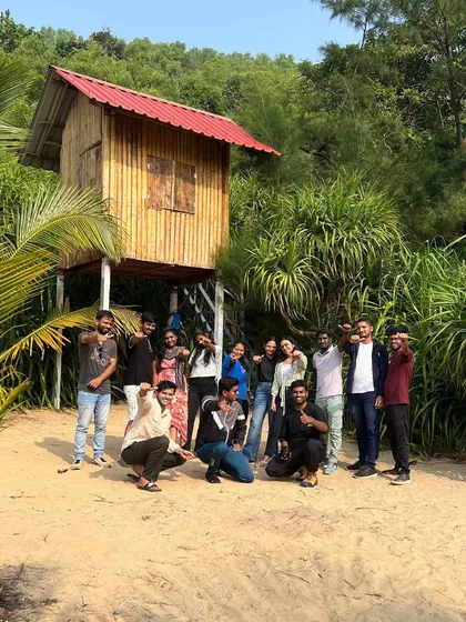 Our group posing in front of a cool treehouse on the beach, a unique find during our coastal exploration.