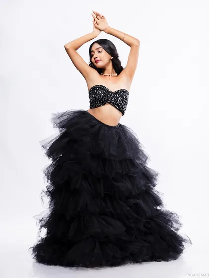 A dramatic full-length portrait of a model in a black sequin top and a voluminous tulle skirt. This is a perfect look for evening wear or a high-fashion editorial.