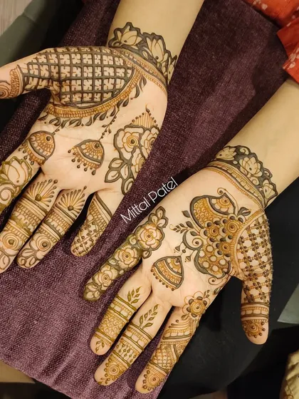 A fancy designer front-hand mehndi combining floral vines with traditional jhumka and checkerboard patterns. This asymmetrical design is modern and eye-catching.