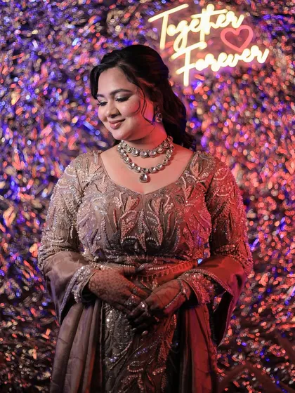 A sweet photo of the bride under a 'Together Forever' neon sign, capturing the romantic mood of the evening.