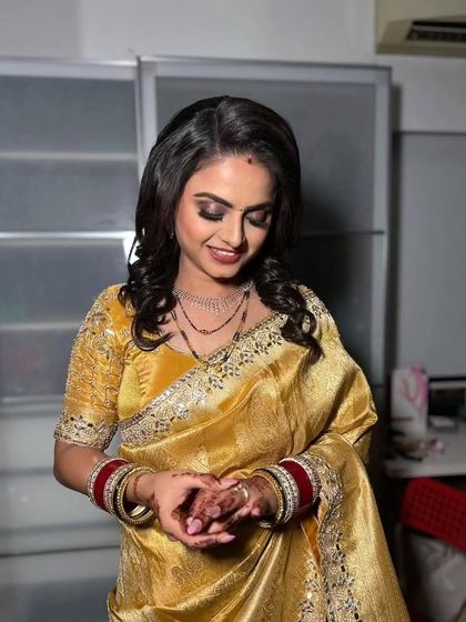 A classic reception look in a golden-yellow saree. The makeup features a soft smokey eye and a glossy lip, creating a warm and inviting look.