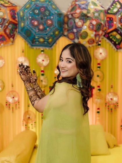 A beautiful bride posing at her mehendi function, with a vibrant, festive background that complements her henna.