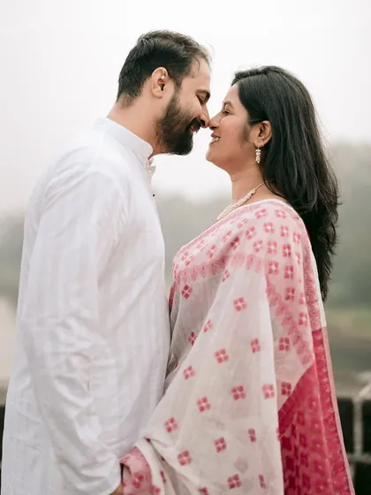A classic, romantic close-up. The soft, misty background of the river contrasts with the sharp, happy connection between Chaitrali and Parth.