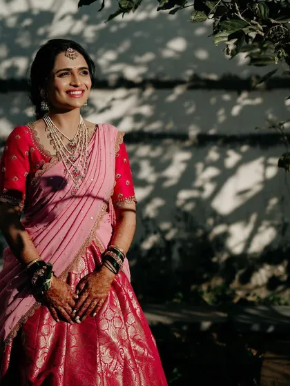 A bride in a pink half-saree, enjoying a moment in the sun. Her custom red blouse provides a beautiful contrast to the pink skirt.