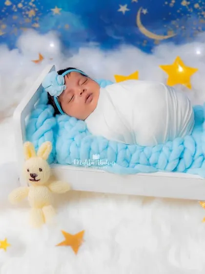 A beautifully swaddled newborn sleeping soundly in the miniature bed, creating a peaceful and angelic portrait.