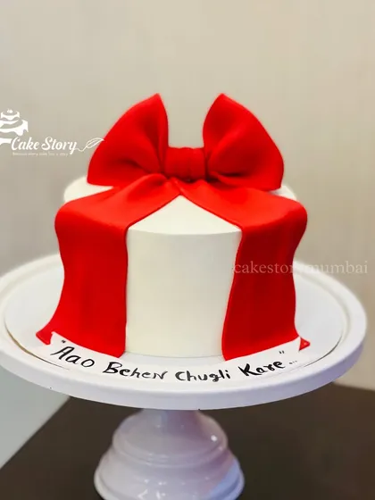 An all-edible bow cake with a funny message, 'Aao Behen Chugli Kare' (Come sister, let's gossip). The big red bow is handcrafted from fondant.
