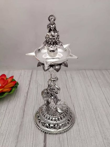 An antique-finish Lakshmi diya with an elephant base. This German silver piece combines several auspicious symbols, making it a powerful item for your altar.