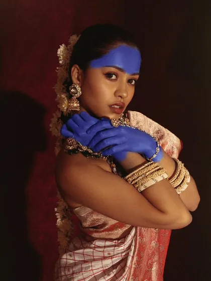 A close-up portrait from the same series, showing the contrast between the model's soft expression and the bold, unconventional makeup. The jasmine in her hair adds a traditional touch.