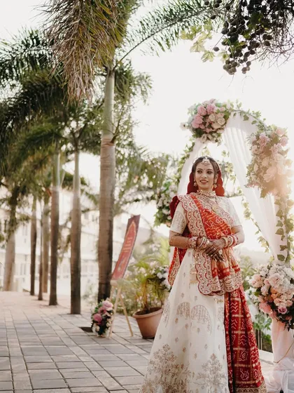 A beautiful solo portrait of the bride at her wedding venue. The floral arch and palm trees create a perfect frame for her elegant look.