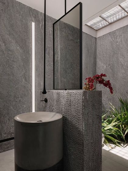 Another angle of the grey stone powder room, showing the custom-designed mirror and tapware. The space is a perfect example of how we use a single material to create a powerful impact.