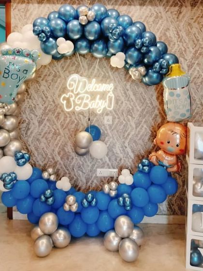 A grand welcome for a baby boy with a full circular balloon ring. The blue, silver, and white balloons are complemented by a "Welcome Baby" neon sign and transparent "BABY" boxes.
