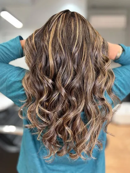 These honey blonde highlights add beautiful warmth and dimension. The curls help to showcase the intricate placement of the color.