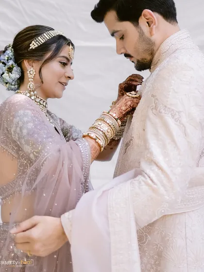 A sweet, candid moment where the bride helps the groom with his outfit. It's these small acts of care that reveal the depth of a relationship.