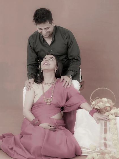 A joyful, candid moment captured during a traditional maternity shoot. The mom-to-be looks up at her partner with a beautiful, happy laugh, a memory they will cherish forever.