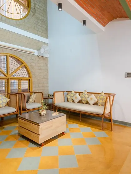 The double-height living area uses a combination of Jaisalmer yellow and grey Kota stone for the flooring. Large arched windows and exposed earth block walls bring in ample daylight and a sense of warmth.