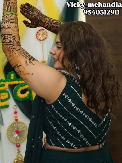 A bride dancing and celebrating at her mehndi function, with her beautiful arm designs on full display.