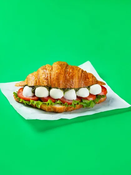 A Caprese croissant sandwich with mozzarella and tomatoes. This image for Bistro by Blinkit uses a clean, high-key lighting setup for a fresh look suitable for digital menus.