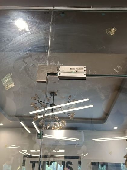 A clear view of the EM lock installed on the glass door, with the gym's stylish interior visible in the background.