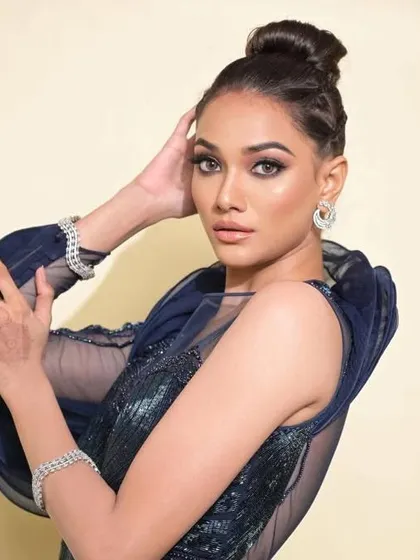 This shot shows the braided-detail bun with a high-fashion navy blue gown. The hairstyle is elegant and modern, suitable for a celebrity or red carpet event.