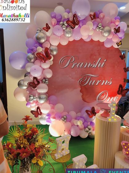 A close up of the butterfly theme for Pranshi's first birthday, showing the detail of the custom backdrop and balloon colors.