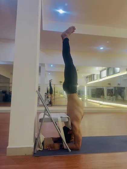 Props are intelligent tools for learning. Here, I use a chair, blocks, and a strap to refine the alignment of Pincha Mayurasana (Forearm Stand), ensuring the shoulders are stable and the spine is long.