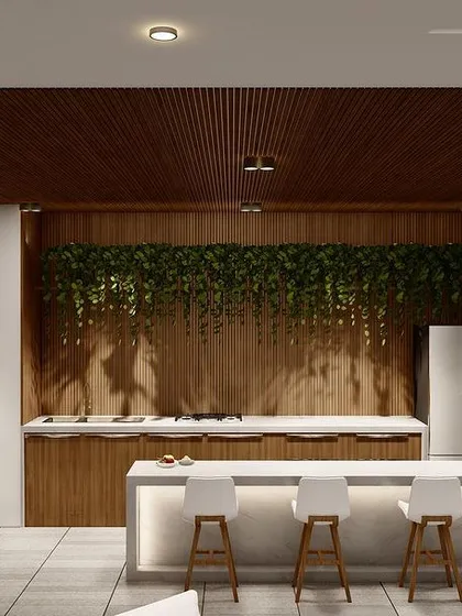 A view of the bar and kitchen area within the covered terrace lounge in Punjabi Bagh. The design uses a mix of wood paneling, marble countertops, and integrated lighting.