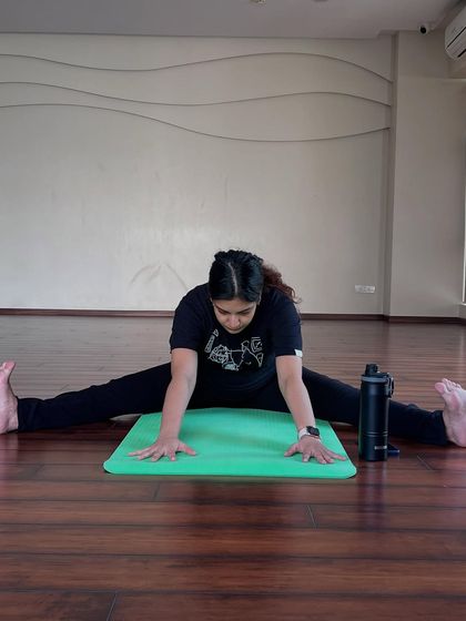 Here, a mother-to-be works on a wide-legged forward bend, or Upavistha Konasana. This pose is invaluable for increasing flexibility in the hips and preparing the body for childbirth.