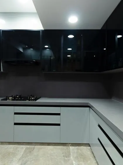A modern kitchen with a striking contrast between matte grey lower cabinets and glossy black upper cabinets. The design is clean, minimalist, and highly functional.