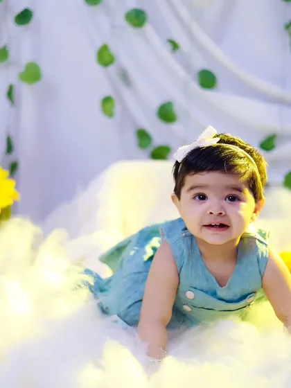 A happy baby girl crawling through a field of soft clouds and sunflowers in our studio. Sitter sessions are full of movement and discovery.