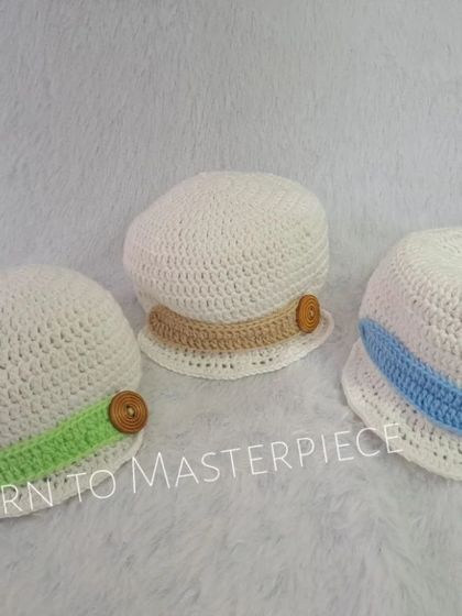 These classic baby caps are perfect for any little one. Made from soft white cotton yarn, I offer customization with different colored bands, like the green, beige, and blue shown here.