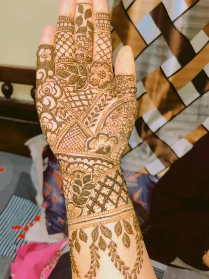 An elegant design for the back of the hand, featuring a mix of traditional Indian motifs and leafy patterns that trail down from the wrist.