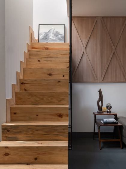 The staircase is framed by slender black balusters, which provide structure while maintaining a sense of openness. The design connects the living area to the upper floor seamlessly.