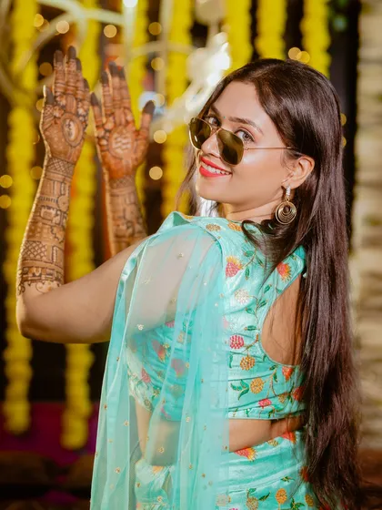 A cool and stylish bride showing off her mehndi with a fun pose and sunglasses. It's all about capturing the mood of the celebration.