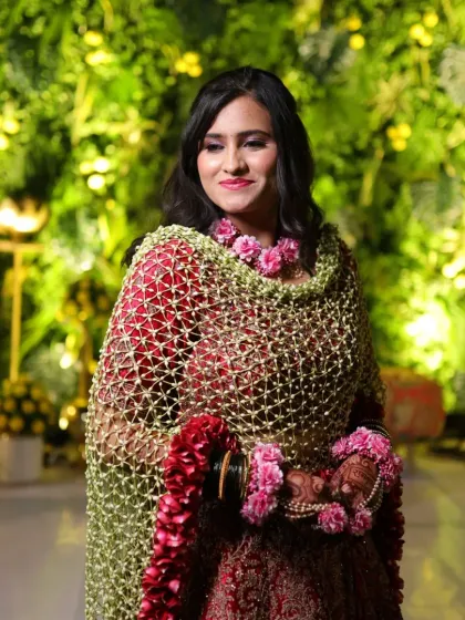 A full view of the bride wearing the red rose border floral shela. It drapes beautifully over her red lehenga, creating a look of pure opulence.