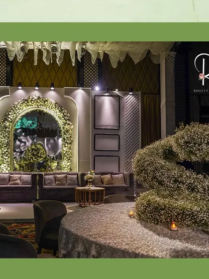 A lounge area with a custom centerpiece made of baby's breath, spelling out the letter 'S'. The tables are covered in a sparkling, textured linen.