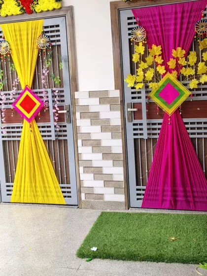 For pre-wedding functions at home, I create vibrant and traditional decor. Here, I've decorated two entrances for a Haldi or Mehendi ceremony using bright yellow and magenta drapes, complemented by traditional hangings and floral elements.