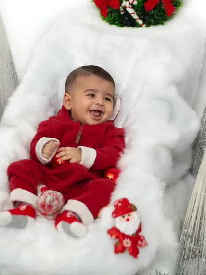 A happy baby enjoying his first Christmas themed shoot. The simple setup with festive props creates a magical winter wonderland scene for his portraits.