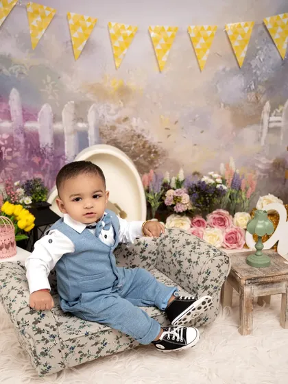 A dapper little man sitting in his floral armchair. This charming portrait combines a classic outfit with a whimsical, colorful backdrop for a unique look.