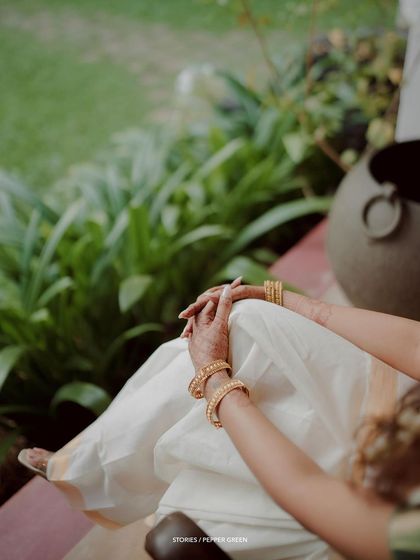 A detail shot of the bride's hands and her beautiful kasavu saree, a moment of quiet elegance.
