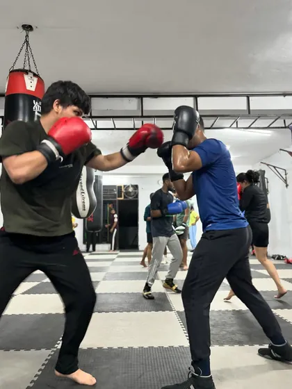 An action shot of a student throwing a powerful right hand during a partner drill. The intensity is high, but the training is controlled.