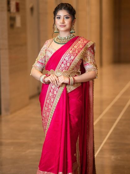 The timeless charm of a red saree. This look is all about royal elegance, featuring soft glam makeup with defined eyes that allows the rich color and intricate work of the saree to take center stage.