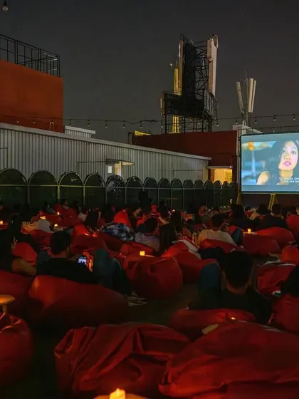 A rooftop screening in Bangalore, where the city skyline becomes part of the backdrop. Watching a movie with the cool evening breeze is an experience you won't forget.
