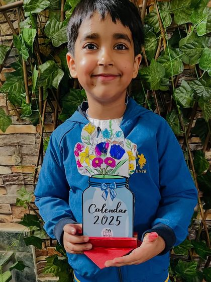 A smiling student with the beautiful floral calendar he made to welcome the new year.