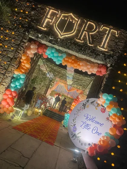A grand entrance for a 'Welcome Little One' event at The Fort. A colorful balloon arch frames the rustic stone entrance, creating a beautiful contrast.