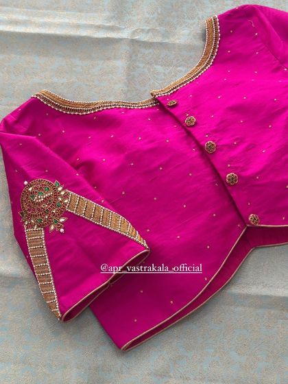 A modern take on the jewellery concept, this pink blouse has flared sleeves with a statement motif.