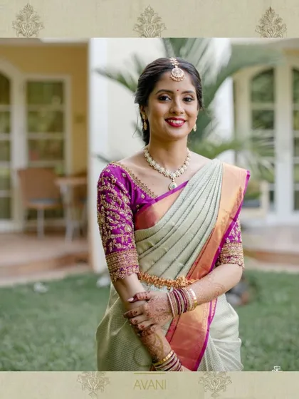 A bride in a light green saree with a magenta blouse. The heavy embroidery on the blouse makes it a statement piece in her ensemble.
