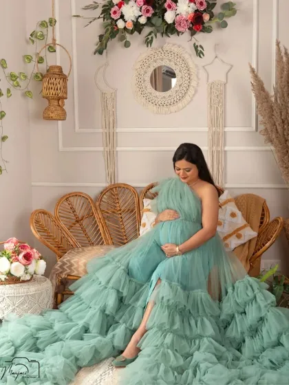 A serene solo portrait. The mama-to-be looks peaceful and content as she cradles her bump in the cozy boho corner of my studio.