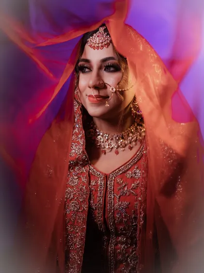 A creative shot with a flowing red veil. The vibrant colors and the bride's serene expression make for a truly captivating bridal portrait.