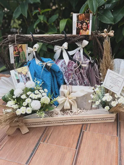 A wider view of the hanger hamper, showcasing the full arrangement on a rustic tray. The combination of natural textures, soft florals, and personal mementos makes this a heartfelt and creative gift.